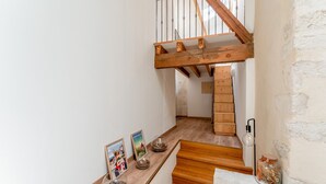 A staircase with wooden steps and a wooden handrail, leading to a landing with a white wall and a small shelf with decorative items. - Guest Room “Coquelicot” with Wi-Fi and Air Conditioning (Domazan)