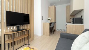 Una sala moderna con una televisión de pantalla plana, un sofá gris y un mueble de entretenimiento de madera.