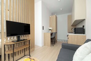 Ein modernes Wohnzimmer mit einem Flachbildfernseher, einem grauen Sofa und einer Holz-Unterhaltungsecke.