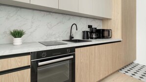 A modern kitchen with a marble backsplash, black faucet, and stainless steel appliances. - Comfortable Studio in the Heart of Katowice | Remote Work Space (Katowice)
