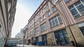 A street view with a building featuring large windows, a trash bin, and a cart. - Comfortable Studio in the Heart of Katowice | Remote Work Space (Katowice)