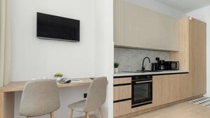 A modern kitchen with a built-in oven, a coffee maker, and a flat-screen TV mounted on the wall. - Comfortable Studio in the Heart of Katowice | Remote Work Space (Katowice)
