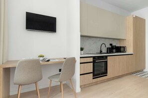 Eine moderne Küche mit Einbauofen, einer Kaffeemaschine und einem an der Wand befestigten Flachbildfernseher.
