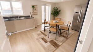 A modern kitchen with a dining area, a built-in oven, and a refrigerator. - House Sleeps 12 With Wifi (Bristol)