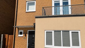 A two-story residential building with a brick facade, a black door, and a small balcony with a metal railing. - House Sleeps 12 With Wifi (Bristol)