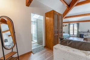 A bedroom with a wooden wardrobe, a bed, a mirror, and a view of a bathroom.