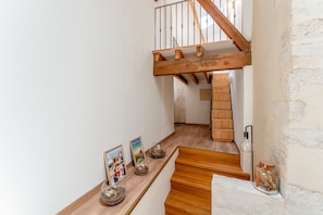 A staircase with wooden steps and a wooden handrail, leading to an upper floor.