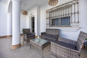 Ein Zimmer mit Korbmöbeln, einem Glastisch und einem dekorativen Metallgeländer.