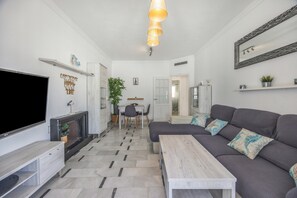 Ein modernes Wohnzimmer mit Flachbildfernseher, Kamin, Sofa und Essbereich mit Tisch und Stühlen.
