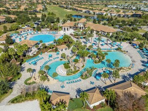 Ein Luftbild eines Resorts mit mehreren Swimmingpools, Liegestühlen und Palmen.