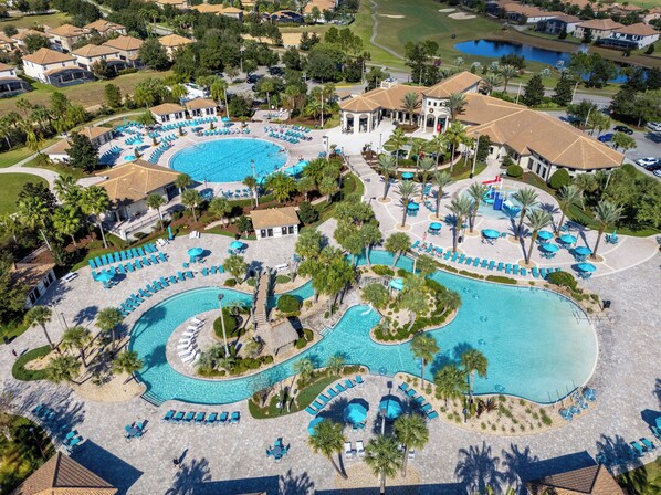 Ein Luftbild eines Resorts mit mehreren Schwimmbecken, Liegebereichen und Palmen.
