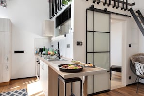 A modern kitchen with a central island, a dining area with a chair, and a sliding door.