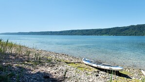A calm lake with a rowboat on a rocky shore.