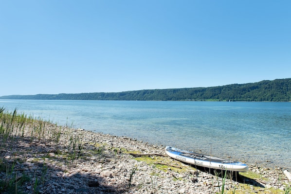 A calm lake with a rowboat on a rocky shore.