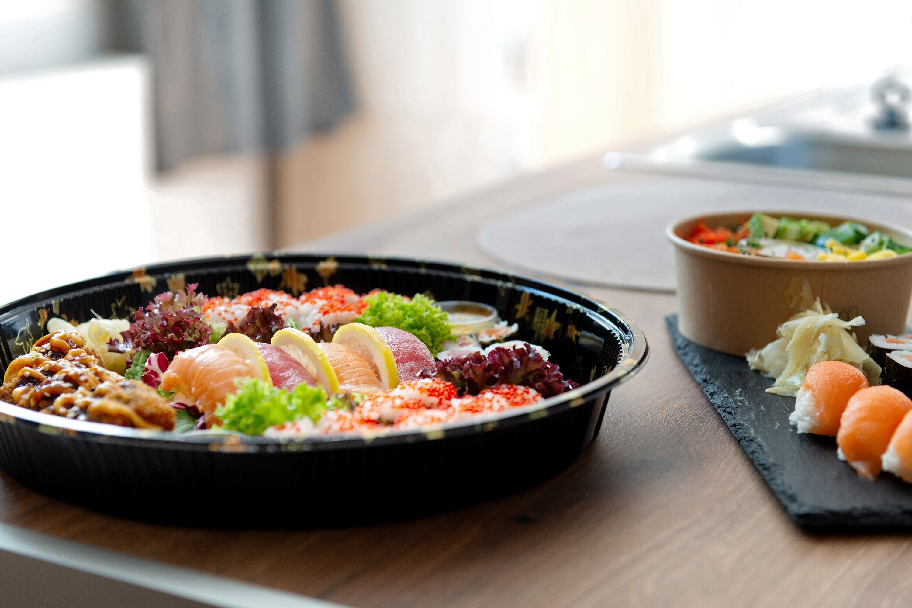 Un repas composé de différents plats, notamment des sushis, des sashimis et des légumes, servis sur une table en bois.