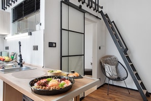 A modern kitchen with a dining area, a black chair, and a staircase. - Apartment Myraybay near the Lake with Wi-Fi and Optional Swimming Area (Stockach)
