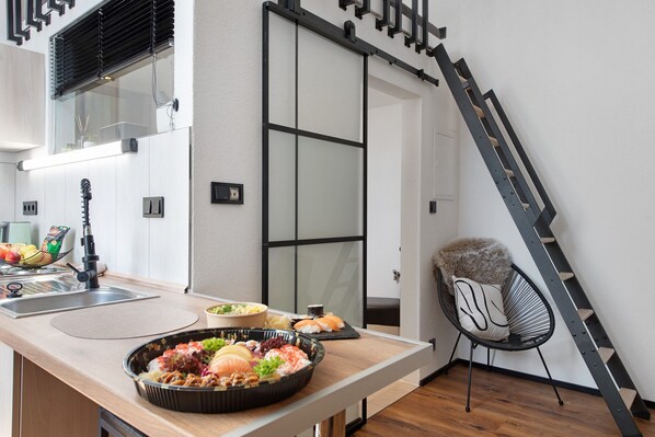 A modern kitchen with a dining area, a black chair, and a staircase.