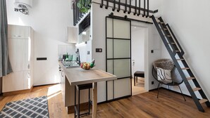 Eine moderne Küche mit Holztisch, schwarzem Stuhl und einer Treppe.