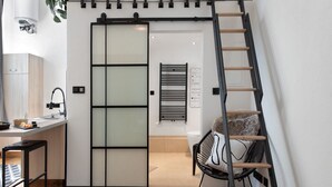 Ein modernes Interieur mit einer Schiebetür, einer Leiter, einem Stuhl und einem kleinen Tisch mit einer Pflanze.