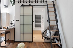 A modern interior with a sliding door, a ladder, a chair, and a small table with a plant.