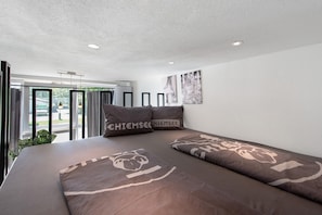 A modern bedroom with a large bed, two pillows, a ceiling light, and a window with curtains. - Apartment Myraybay near the Lake with Wi-Fi and Optional Swimming Area (Stockach)