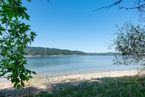 A lake with a rocky shore, surrounded by greenery and hills.