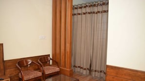 A room with two wooden chairs, a glass table, and a curtain with a geometric pattern.