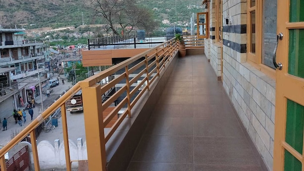 A balcony with a view of a mountainous landscape, a tiled floor, and a railing.