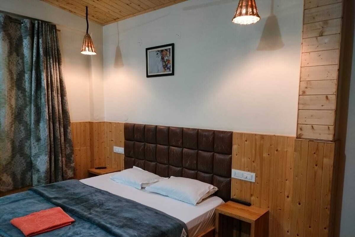 Un dormitorio con cabecera de madera, una cama con ropa de cama blanca, una mesita de noche y un velador.