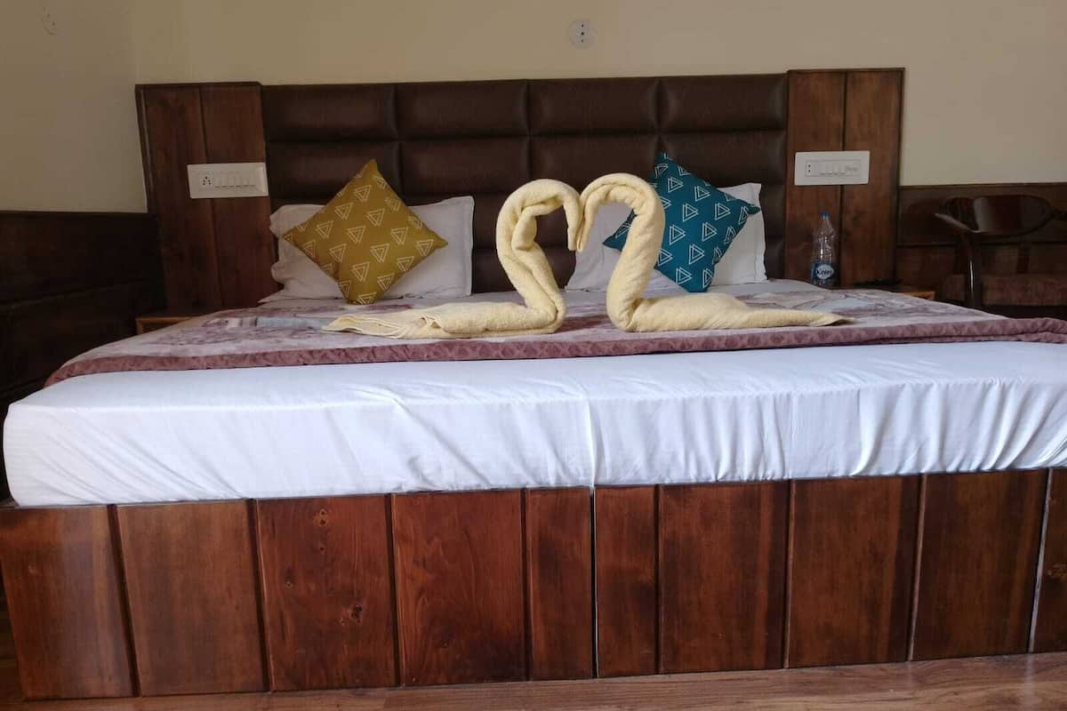 Una cama con cabecera de madera, ropa de cama blanca y almohadas decorativas.