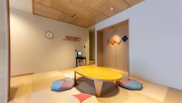 Een kamer met tatami vloerbedekking, een lage houten tafel en kussens.
