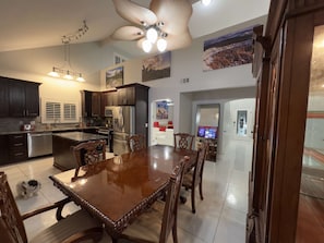 A modern kitchen with dark cabinetry, stainless steel appliances, and a dining area with a wooden table and chairs.