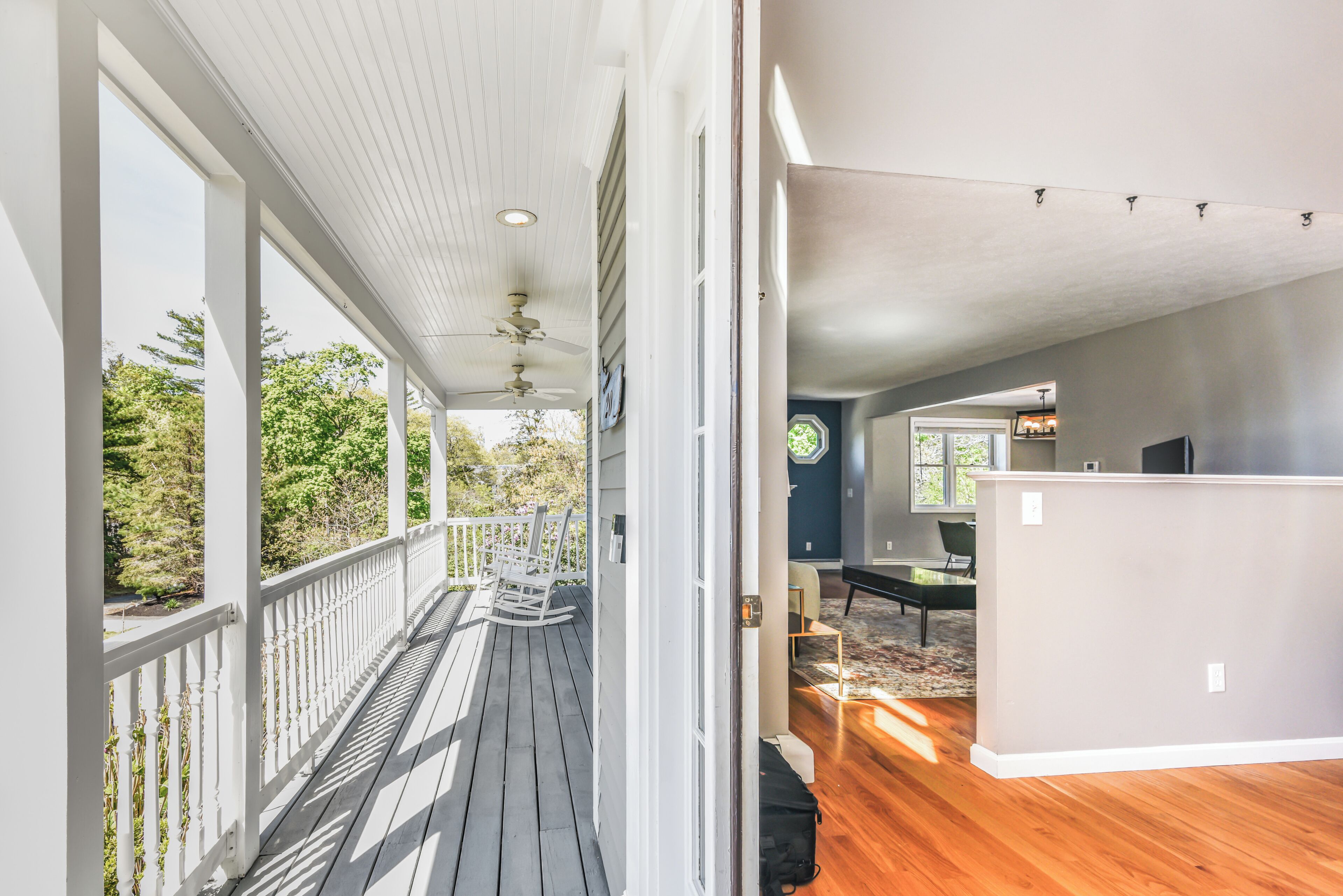 A covered porch with a ceiling fan, a view of the outdoors, and a room with a desk and chair.