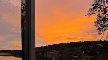 Una terraza de madera con un banco y una mesa, con vista a un lago al atardecer.