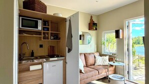 Ett kompakt bostadsutrymme med ett litet kök, en soffa och utsikt över omgivningarna.
