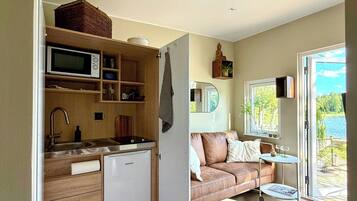 Un espacio habitable compacto con kitchenette, un sofá y vistas al exterior.