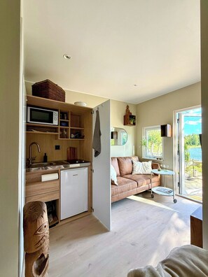 Un espacio habitable compacto con kitchenette, un sofá y vistas al exterior.