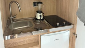 Ett litet, praktiskt kök med mikrovågsugn, mixer, diskho och ett litet kylskåp.