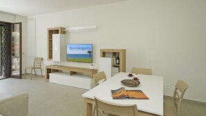 Una sala de estar moderna con un televisor de pantalla plana, una mesa de comedor y una estantería.