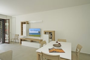Ein modernes Wohnzimmer mit einem Flachbildfernseher, einem Esstisch und einem Bücherregal.