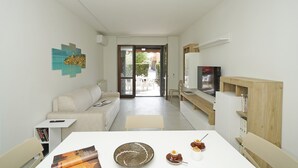 Una sala de estar moderna con un sofá, una mesa de centro, un televisor y una estantería.