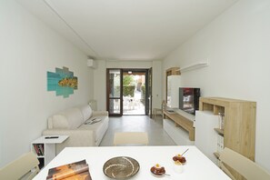 Ein modernes Wohnzimmer mit einer Couch, einem Couchtisch, einem Fernseher und einem Bücherregal.