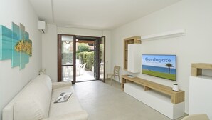 Una sala moderna con un sofá, un televisor de pantalla plana y un banco de madera.