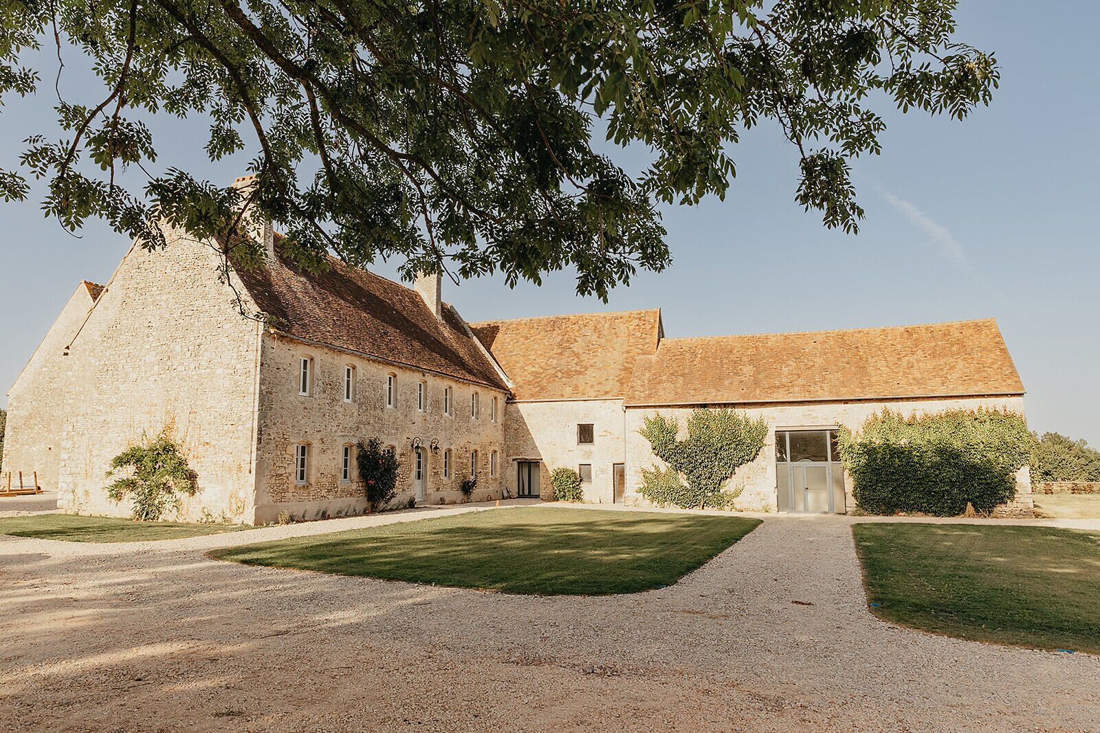 Un bâtiment en pierre avec une allée en gravier et une pelouse bien entretenue.