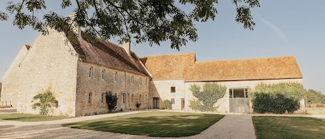 A stone building with a gravel driveway and a well-maintained lawn.