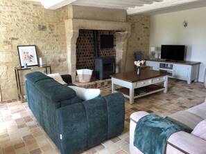 Ein Wohnzimmer mit einer Couch, einem Couchtisch, einem Kamin, einem Fernseher und einer Steinwand.