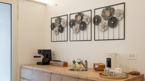 A kitchen with a coffee machine, kettle, and decorative wall art.