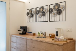 Una cocina con cafetera, hervidor y decoración mural.
