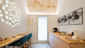 A modern kitchen with a wooden countertop, a coffee machine, and a view of the outside through a glass door.