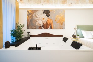 A hotel room with a large bed, a headboard, a wall-mounted painting, a bedside table, a lamp, and a green headboard. - Room 'Celine Dimora e Suite' with Jacuzzi, Sky TV, Wi-Fi, and Air Conditioning (Copertino)